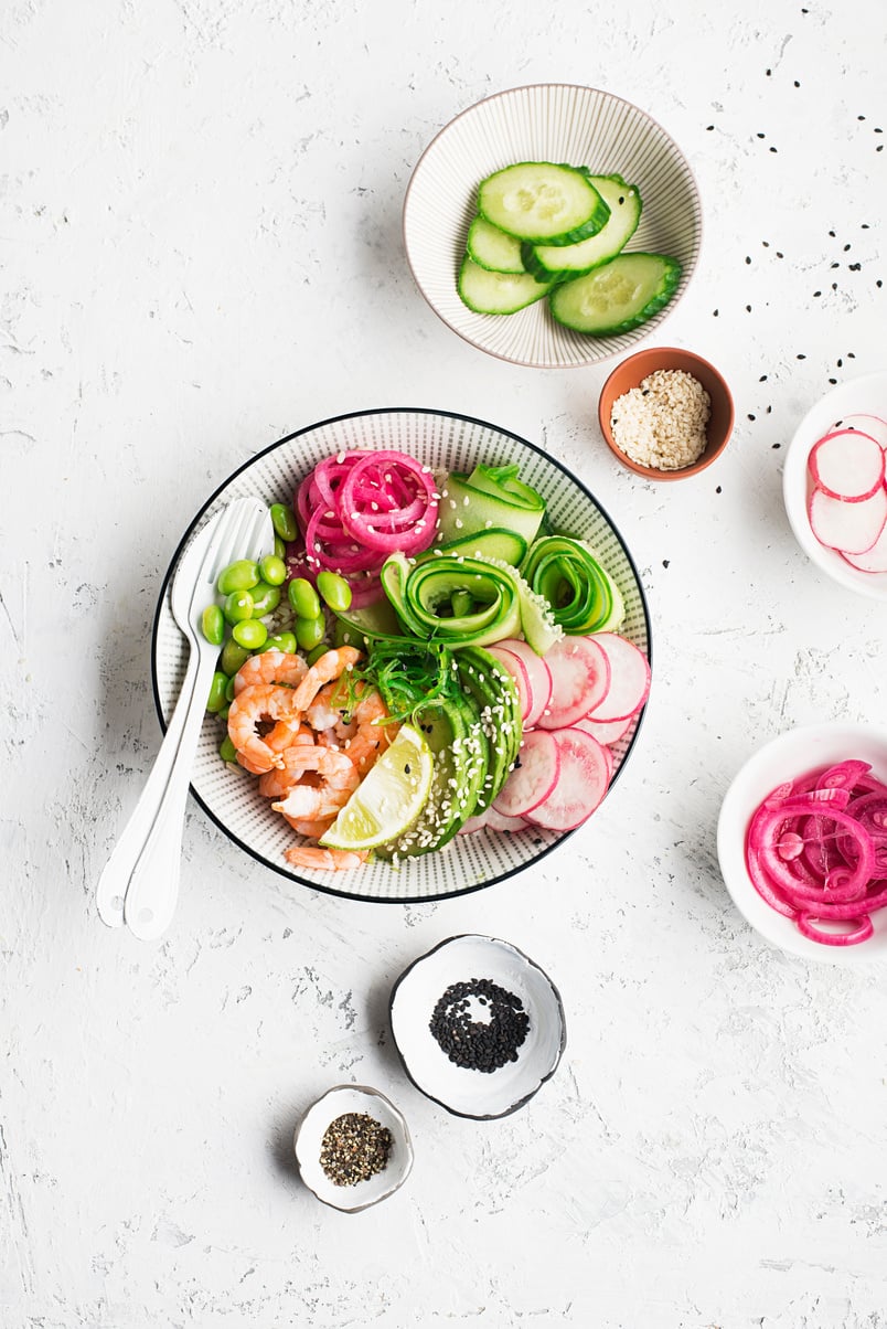 Fresh seafood recipe. Shrimp poke bowl with fresh prawn, brown rice, cucumber, pickled sweet onion, radish, soy beans edamame portioned with black and white sesame. Food concept poke bowl